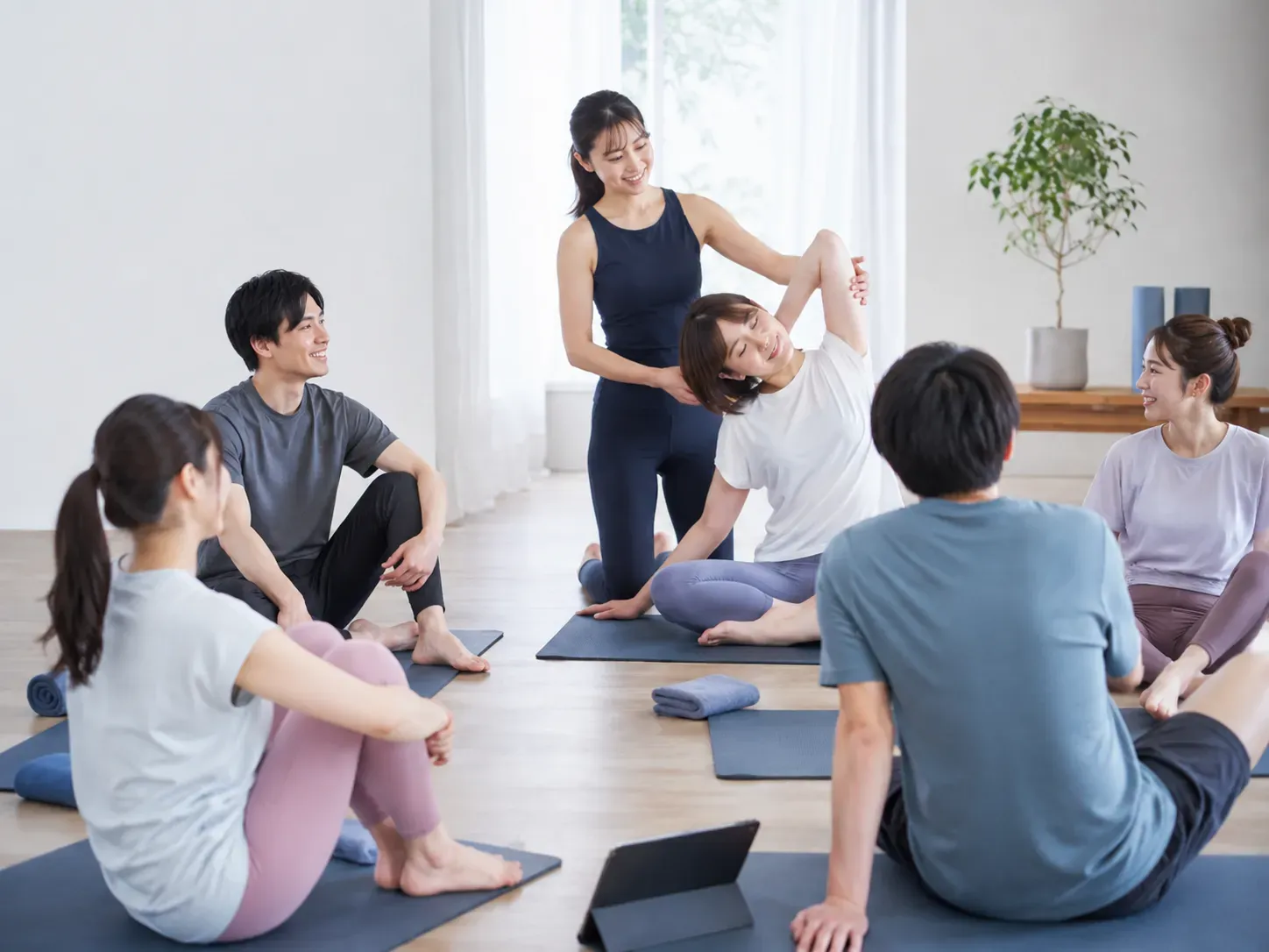 トレーナーと複数の会員が小規模なストレッチレッスンを楽しむ様子